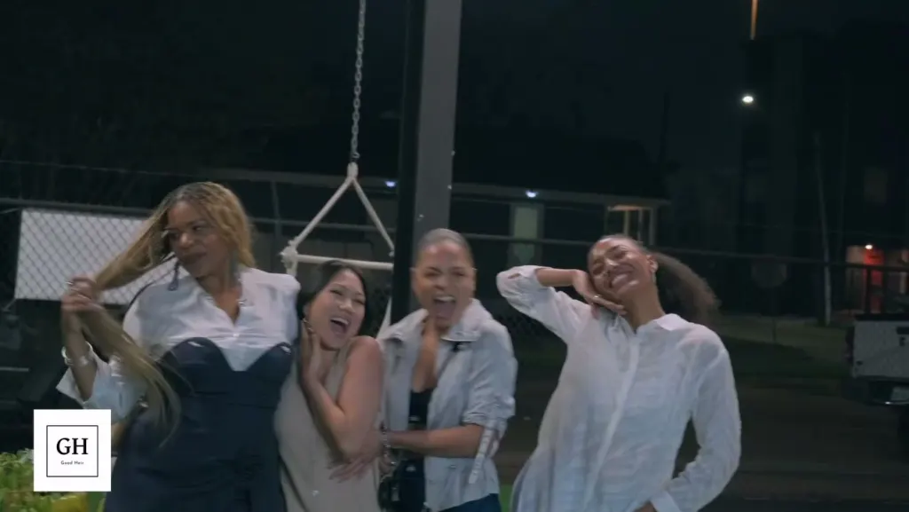 Four friends laughing and posing on the turf yard at night during a garden event