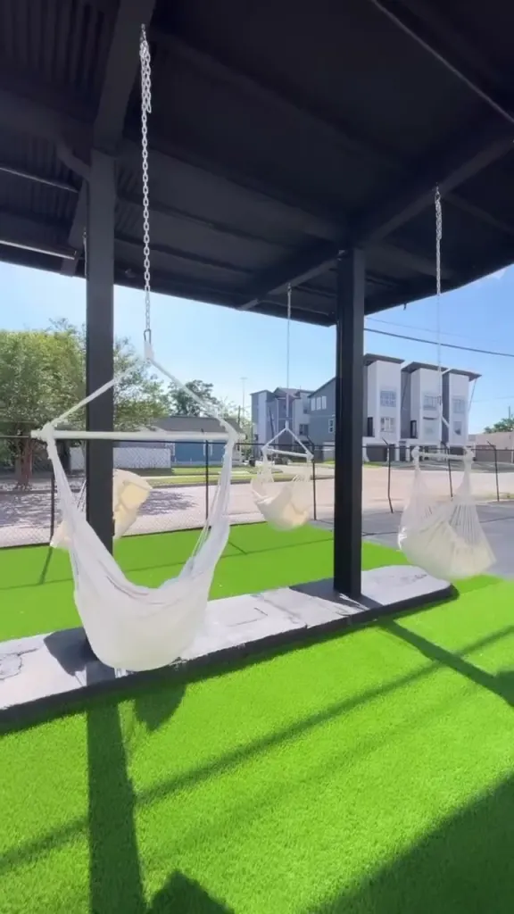 white hammock chairs swaying under the covered pavilion on the turf yard
